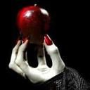 a woman holding an apple up to her face in front of a black background with white hands