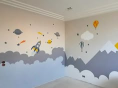 an empty room with painted clouds, hot air balloons and rockets on the wall in it