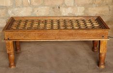 an old wooden table with chess pieces on it in front of a stone wall and floor