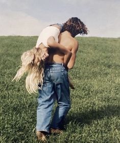 a man carrying a woman on his back in the middle of a grass covered field