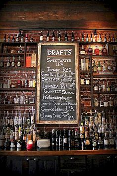 a bar with lots of bottles on the wall and a chalk board in front of it