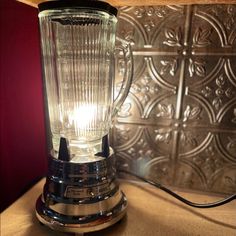 an old fashioned blender sitting on top of a table next to a light bulb