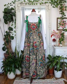 "This elegant corset dress is made from a vintage cotton and linen blend fabric from 1988. It has a beautiful floral vase motif and the quality of the fabric is truly exceptional. The corset is fully boned and lined with white cotton. The back of the dress is laced up with gold grommets and a green ribbon. This dress has large pockets, making it practical as well as beautiful.  The pattern placement on each dress will be slightly different, making each piece unique. But all dresses will feature the same floral print in the centre front of the corset.  The corseted bodice reduces your measurements by approximately 2\" when laced tightly, so it's recommended to choose a size around 2\" smaller than your natural measurements if you want a cinching effect. Please check the size chart for more Cotton Dress With Fitted Bodice, Elegant Corset Dress, Vintage Cottagecore Dress Corset, Floral Print Overbust Corset With Fitted Bodice, Vintage Floral Print Fitted Corset, Elegant Corset, Cottagecore Floral Patchwork Dress, Vintage Overbust Floral Print Corset, Floral Vase