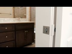 an open door leading to a bathroom with brown cabinets and marble counter tops in the background