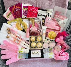 a basket filled with lots of items on top of a pink blanket next to a pair of gloves