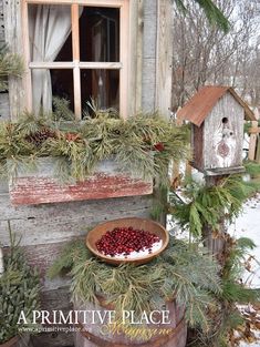 a wooden window sill filled with berries and greenery next to a birdhouse