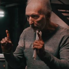 an old man holding a toothbrush in his right hand and making the peace sign