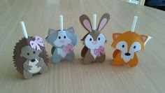 four paper animals sitting on top of a wooden table next to candles with sticks sticking out of them