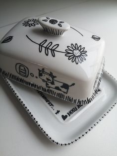 a white cake sitting on top of a plate next to a cupcake holder with black and white designs