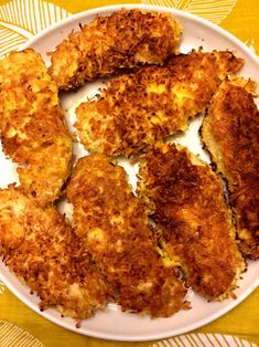 some fried food on a white plate on a yellow table cloth with a fork and knife