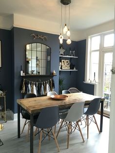 a dining room with blue walls and wooden table surrounded by chairs in front of it