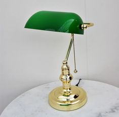 In stock Delivery time 2-6 days With pull switch E27 fitting Tiltable lampshade A real classic Banker's lamp with a drawstring. This banker's lamp can be used as a table lamp and as a desk lamp. Our best-selling version is manufactured after the original model, including the green glass shade (safety glass), drawstring and the brass base. You can turn the banker's lamp on and off with the brass chain. Our drawstring banker's lamp comes in a great presentation box and is a super luxurious gift, a Dark Green Office, Dorm Desk Decor, Bankers Desk Lamp, Dorm Desk, Lampe Vintage, Green Desk, Bachelorette Pad, Bankers Lamp, Desk Lamp Office