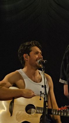 a man holding a guitar and singing into a microphone