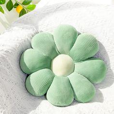 a green flower shaped pillow sitting on top of a bed