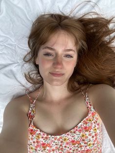 a woman laying on top of a bed with her hair blowing in the wind and eyes closed