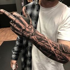 a man is holding his hand up to show off the tattoos on his arm and wrist