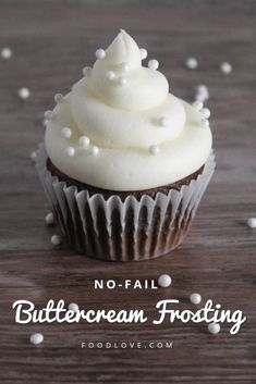 a chocolate cupcake topped with white frosting and sprinkles on a wooden table