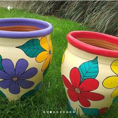 two painted flower pots sitting in the grass