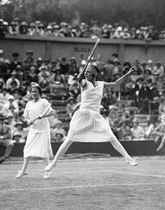 a woman holding a tennis racquet on top of a tennis court in front of a crowd