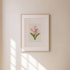 pink flowers are displayed in a white frame on the wall