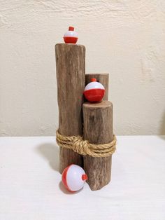 three pieces of wood with red and white balls on them, tied together to each other