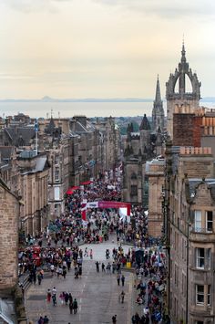 an aerial view of people walking on the street in front of old buildings with tall spires