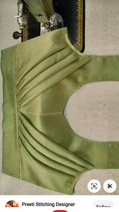 the back of a green dress being sewn with scissors and sewing needles on it