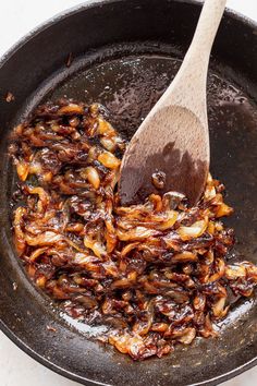 a frying pan filled with cooked onions and a wooden spoon in the skillet