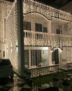 a house covered in christmas lights and decorated with potted plants