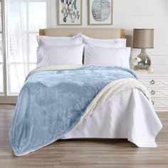 a blue and white comforter on a bed in a room