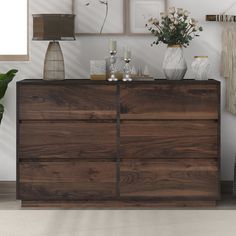 a large wooden dresser sitting next to a wall with pictures on the wall above it