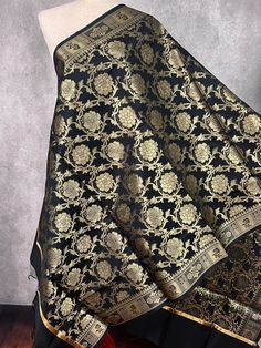 Gorgeous Black Color floral Jaal Banarasi Dupatta with Muted Gold Zari Weave. Dupatta is Soft and will add beauty to any Outfit. Makes a Perfect Gift! Please note - Dupatta has black color tassles on the ends. Item: DupattaColor : Black with Muted Gold Zari Weaving Fabric : Banarasi Silk (Non Pure Silk)Work : Zari Weaved with tassels Length of the dupatta : 88 inches (approx)Width of the dupatta : 35 inches (approx)Store Policies- No return or exchange will be accepted for color variations.- No Black Banarasi Silk Blouse Piece For Eid, Elegant Black Brocade Dupatta, Black Dupatta With Traditional Drape, Black Dupatta With Traditional Drape For Transitional Season, Transitional Season Black Dupatta With Traditional Drape, Black Brocade Traditional Wear With Zari Work, Transitional Black Dupatta With Traditional Drape, Festive Black Dupatta Shawl, Black Brocade Dupatta For Wedding