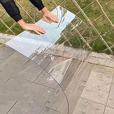 a skateboarder is doing tricks on the edge of a glass ramp in front of a fence