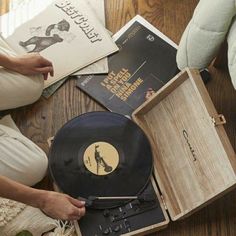 a woman sitting on the floor next to an old record player and other items that have been placed around her