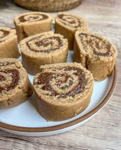 several cinnamon rolls on a white plate with brown trim