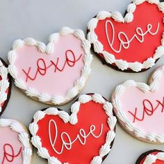 heart shaped cookies with the word love spelled in red and white icing on them