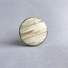 a small wooden button sitting on top of a white cloth covered table next to a gray wall