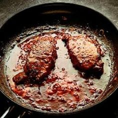 two pieces of meat are cooking in a skillet on top of the stovetop