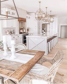 a dining room table and chairs in front of an open kitchen area with white cabinets