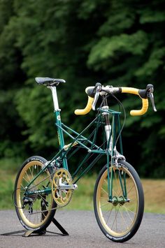 a green and yellow bike parked on the side of a road next to some trees