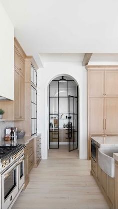 a kitchen with wooden cabinets and marble counter tops, along with an arched doorway leading to the dining room