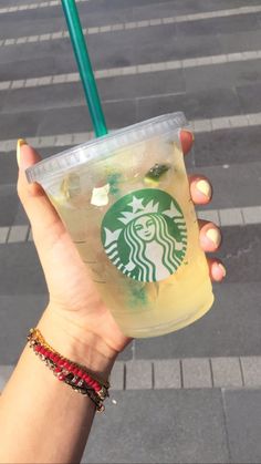 a person holding up a starbucks drink with a straw in it's hand on the street