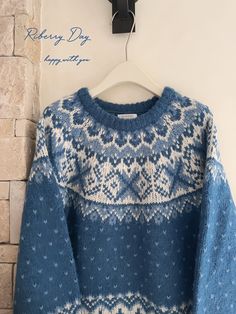 a blue sweater hanging on a brick wall next to a coat hanger with an ornament