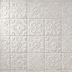 a white tile wall with many different designs on it