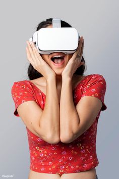 a woman wearing a red top and holding her hands to her face with a white virtual reality headset over her eyes