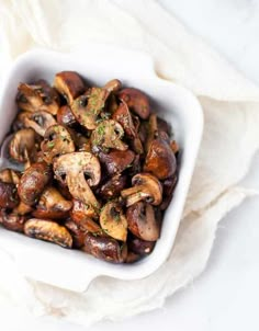 a white bowl filled with mushrooms on top of a table