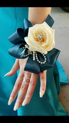 a woman in a blue dress holding a white rose and diamond ring