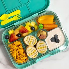 a bento box filled with fruit, vegetables and crackers next to a fork