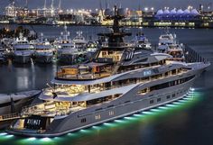 a large white boat is docked in the water at night with other boats around it