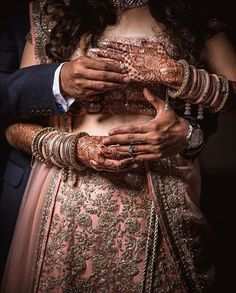 a bride and groom holding each other's hands with their arms wrapped around them